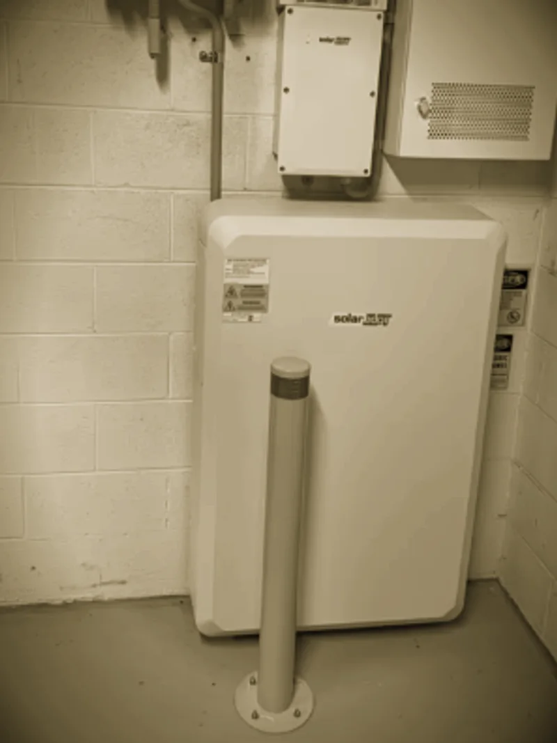 A SolarEdge battery installed by Primero in a garage, behind a bollard