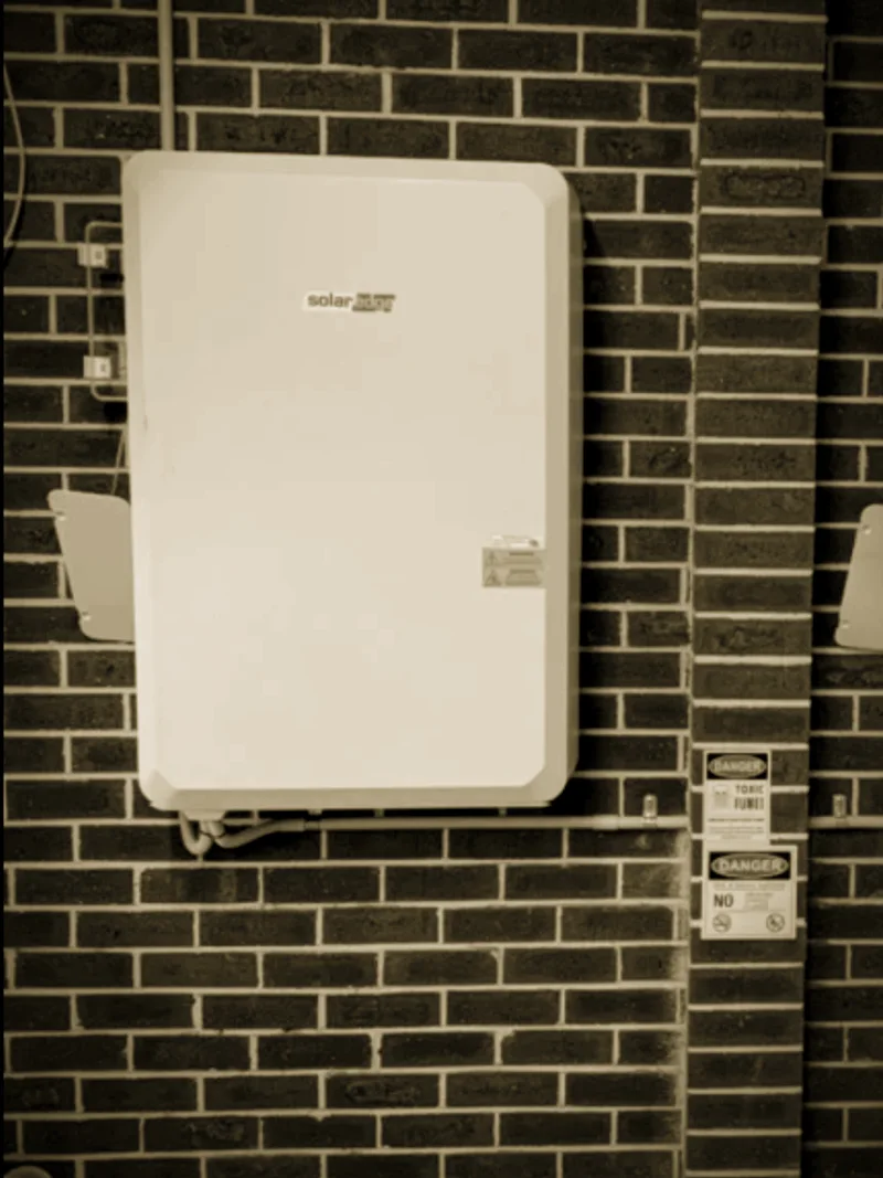 A wall-hung SolarEdge battery installed by Primero on dark brick